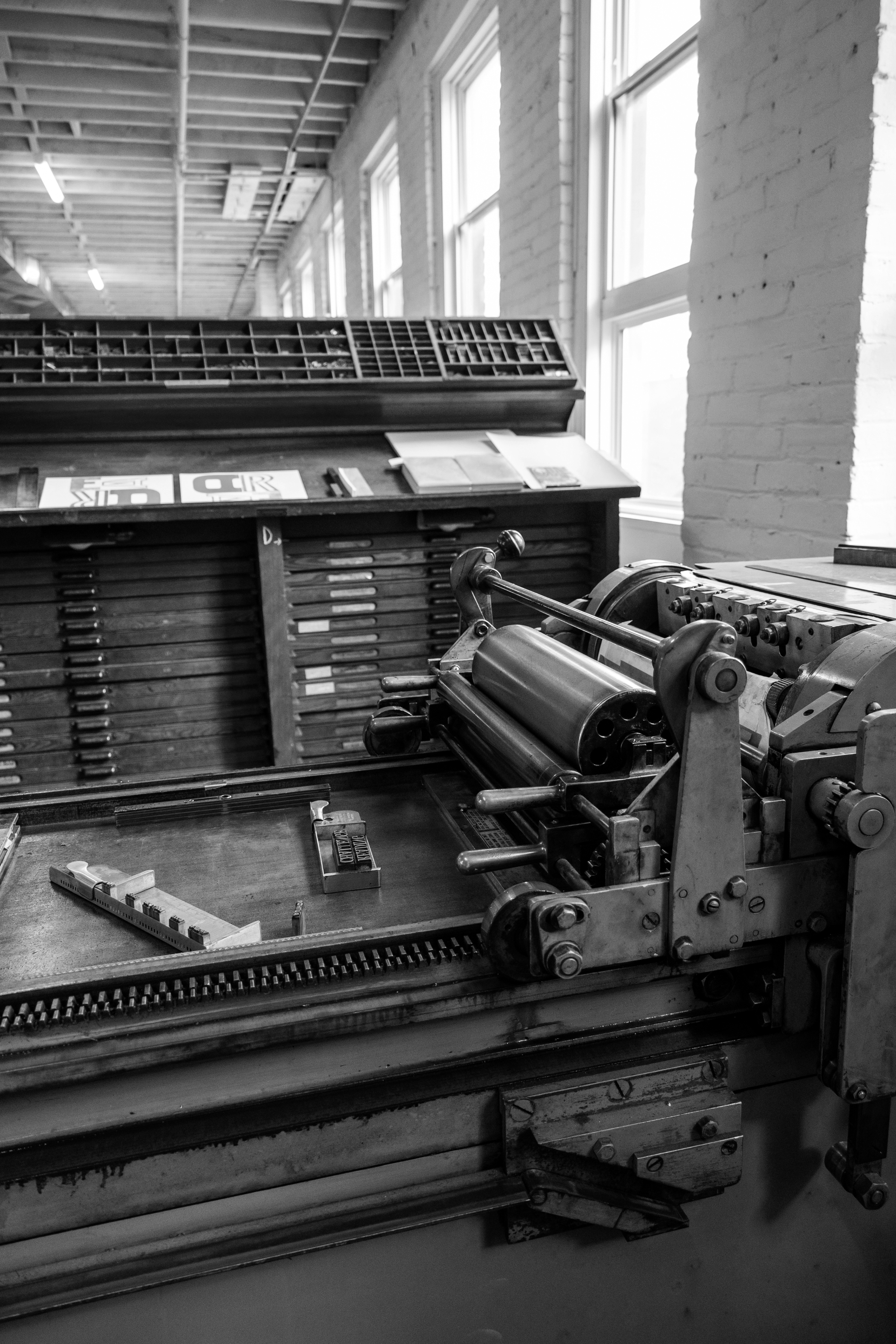 Black and white image of a vintage printing press with type trays and rollers, capturing the industrial spirit of old Nashville in this classic room setting.