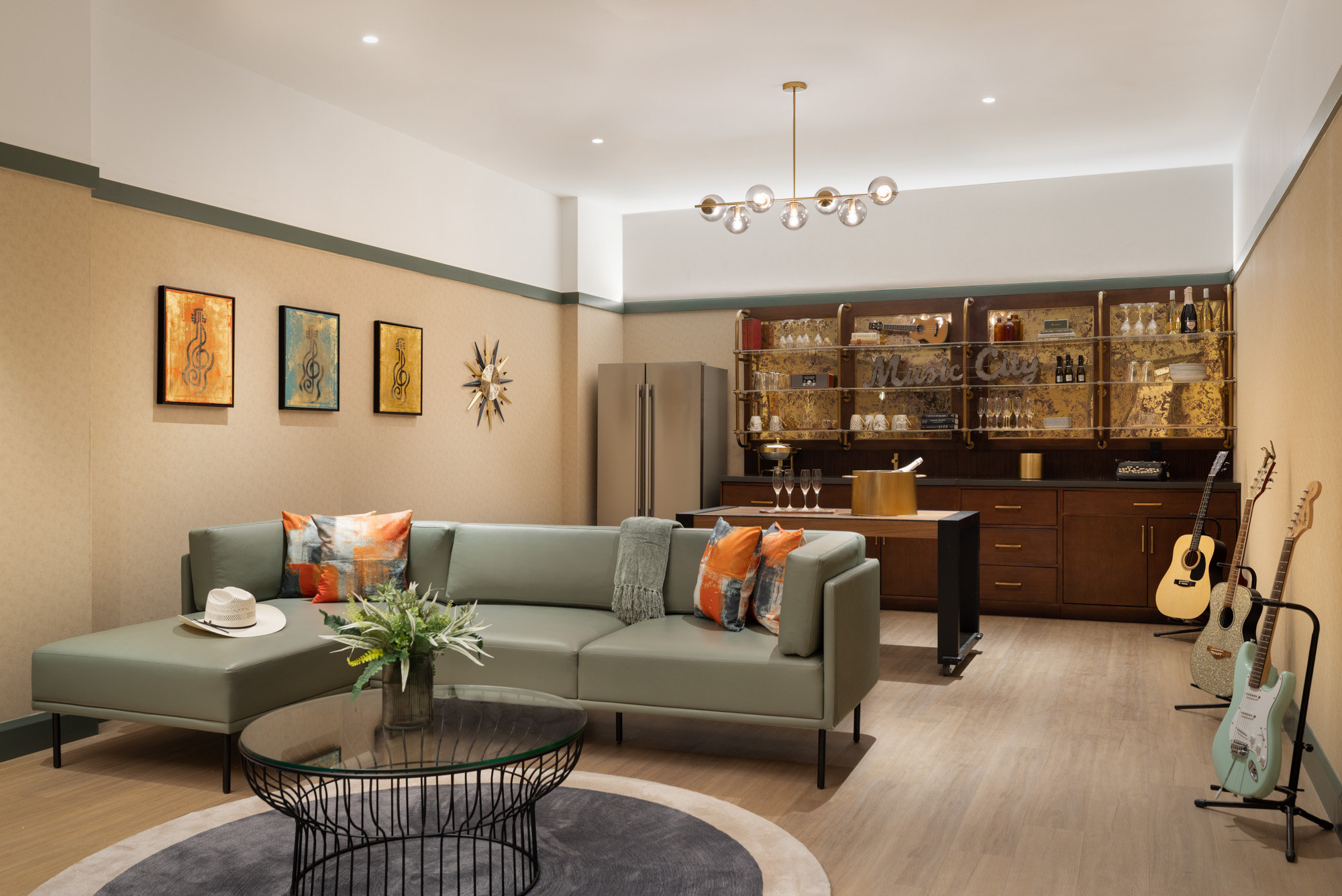 Modern living room with a green sectional sofa, round coffee table, wall art, bar area, musical instruments, and soft overhead lighting.